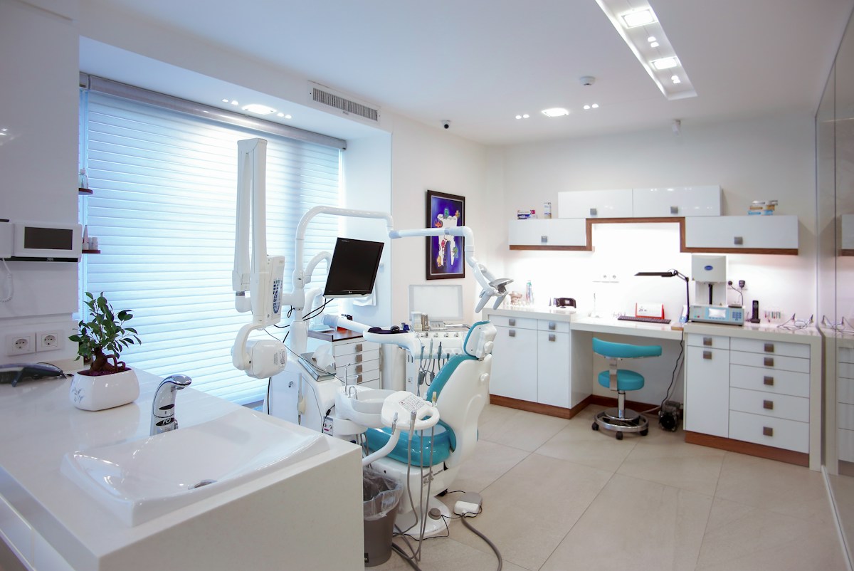 Consultorio luminoso con equipo dental y una silla turquesa